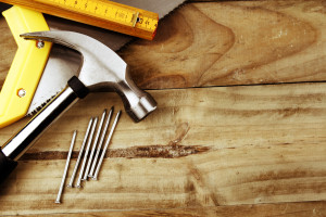 Hammer, nails, saw and folding ruler on wood